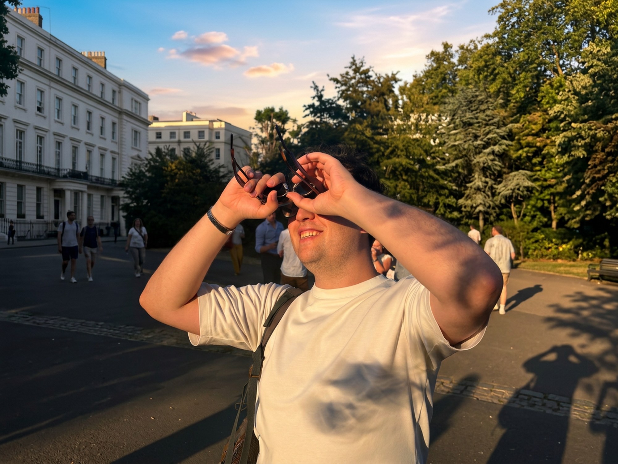 Cemre Efe Karakas shielding his eyes from a low golden sun in a tree-lined London square